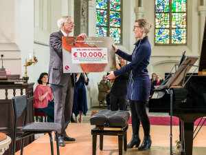 Manon Veenendaal (NMF) ontvangt een cheque van voorzitter Peter Scheerder (Delden Klassiek).